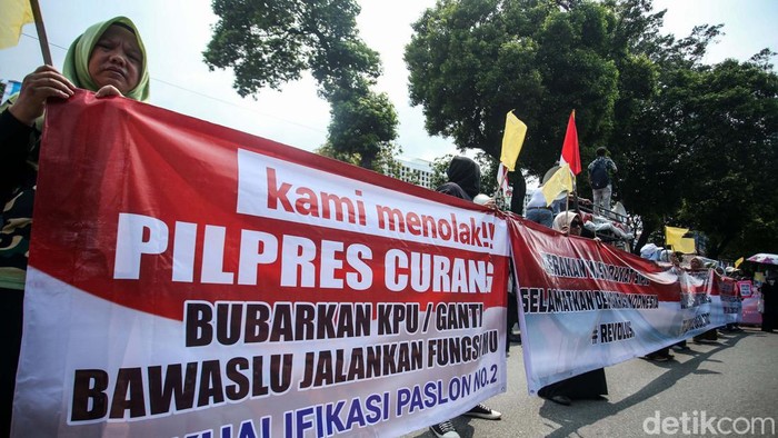 Massa dari Gerakan Masyarakat Sipil menggelar aksi di depan Gedung KPU RI, Jakarta, Senin (19/2/2024). Mereka membawa bendera kuning untuk Jokowi dan KPU.