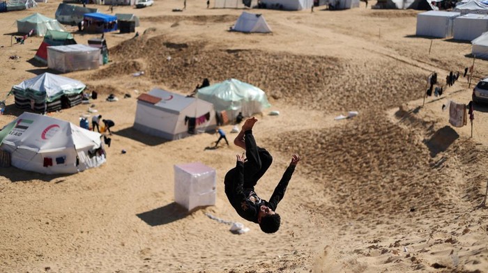 Children walk with a dog, as displaced Palestinians, who fled their houses due to Israeli strikes, take shelter in a tent camp, amid the ongoing conflict between Israel and the Palestinian Islamist group Hamas, at the border with Egypt, in Rafah in the southern Gaza Strip, February 8, 2024. REUTERS/Saleh Salem


     TPX IMAGES OF THE DAY