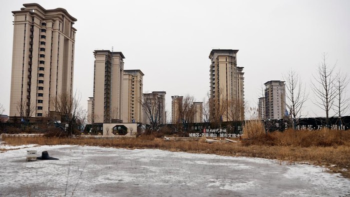 A man walks past unfinished residential buildings developed by China Evergrande Group in the outskirts of Shijiazhuang, Hebei province, China February 1, 2024. REUTERS/Tingshu Wang