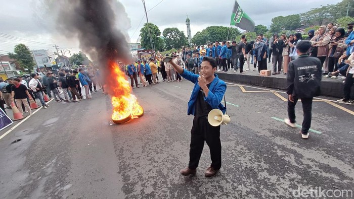 Aliansi mahasiswa Banyumas Raya menggelar aksi dengan membakar ban menyuarakan sistem demokrasi pada pemerintahan Presiden Jokowi di kompleks Alun-alun Purwokerto, Senin (19/2/2023)