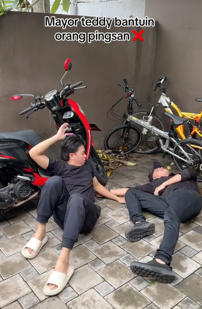 Kocak, kali ini alur video yang dibuat Aiman Ricky berbeda dengan video viral aksi Mayor Teddy. Bukannya membantu orang pingsan, Aiman justru jadi tukeran pingsan karena tak sanggup menggendong orang yang pingsan. Foto: TikTok