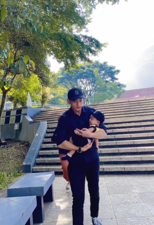 Aktor Vicky Kalea juga ikut memparodikan video Mayor Teddy. Pakai ooutfit mirip serba hitam, Vicky justru menggendong sang anak yang sedang dipangku oleh istrinya, padahal sang istrilah yang berpura-pura pingsan. Foto: TikTok