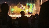 Sejumlah pengunjung menyaksikan pertunjukan air mancur menari dan atraksi formasi drone di danau Archipelago, Taman Mini Indonesia Indah (TMII), Jakarta, Minggu (18/2/2024).