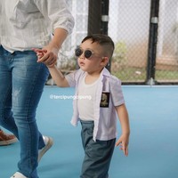 Rayyanza tampil mengenakan seragam SMA putih abu-abu yang dipadukan dengan sneakers putih dan kaca mata hitam. Kemeja yang dikenakannya itu tampak sengaja dibuka dan memperlihatkan kaos dalamnya. Tampil bergaya bak ketua geng, Rayyanza sukses curi atensi. Foto: Instagram/@raffinagita1717