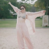 Ketika berlibur di Bali Wulan juga tampak percaya diri memamerkan body goals yang dimilikinya. Lihat saja gayanya saat memadukan bikini top dengan setelan kemeja menerawang berwarna peach. Foto: dok. Instagram/@wulanguritno