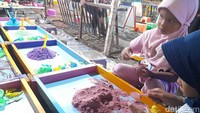 Dua orang anak tampak asyik membuat beragam bentuk dari pasir sintetik.