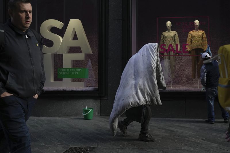 A homeless man walks along a street in a shopping district in central London, Thursday, Feb. 2, 2023. The Bank of England is expected to raise interest rates by as much as half a percentage point Thursday as it seeks to tame the double-digit inflation fueling a cost-of-living crisis, public-sector strikes and fears of recession. (AP Photo/Kin Cheung)