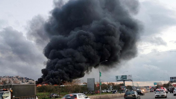 Israel Serang Kota Ghaziyeh Lebanon Vehicles drive as smoke rises from a site hit by an airstrike after what Lebanon's state media said was a series of Israeli strikes, near the town of Ghaziyeh on Lebanon's coast around 60 km north of the border with Israel, Lebanon February 19, 2024. REUTERS/Hassan Hankir NO RESALES. NO ARCHIVES.