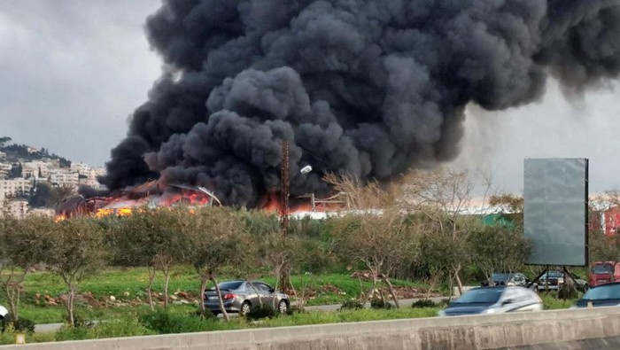 Israel Serang Kota Ghaziyeh Lebanon Vehicles drive as smoke rises from a site hit by an airstrike after what Lebanon's state media said was a series of Israeli strikes, near the town of Ghaziyeh on Lebanon's coast around 60 km north of the border with Israel, Lebanon February 19, 2024. REUTERS/Hassan Hankir NO RESALES. NO ARCHIVES.