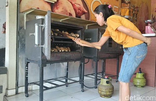 Karyawan UMKM ubi bakar cilembu organik tengah memanggang ubi di Jalan Hayam Wuruk, Denpasar, Bali pada Selasa (20/2/2024). (Ni Made Lastri Karsiani Putri-detikBali)