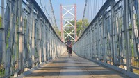 Pengendara sepeda motor melintasi Jembatan Gantung Terkesi di Desa Terkesi, Klambu, Grobogan, Jawa Tengah, Selasa (20/2/2024).