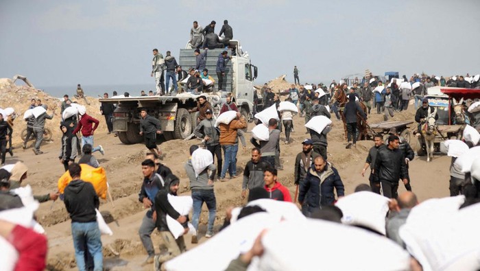 Potret Warga Gaza Berebut Tepung Palestinians carry bags of flour they grabbed from an aid truck near an Israeli checkpoint, as Gaza residents face crisis levels of hunger, amid the ongoing conflict between Israel and Hamas, in Gaza City, February 19, 2024. REUTERS/Kosay Al Nemer
