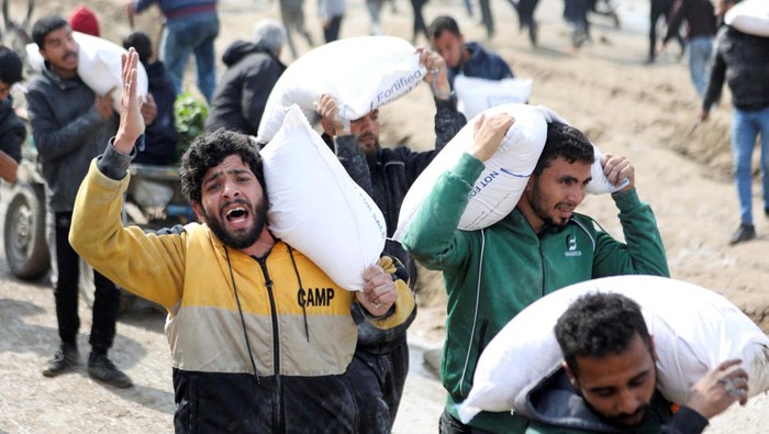 Palestinians carry bags of flour they grabbed from an aid truck near an Israeli checkpoint, as Gaza residents face crisis levels of hunger, amid the ongoing conflict between Israel and Hamas, in Gaza City, February 19, 2024. REUTERS/Kosay Al Nemer
