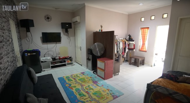 Ruang tengah rumah digunakan sebagai tempat menonton televisi dan bersantai bersama keluarga. Terdapat juga playmat untuk tempat sang anak bermain. Foto: YouTube/Taulany TV