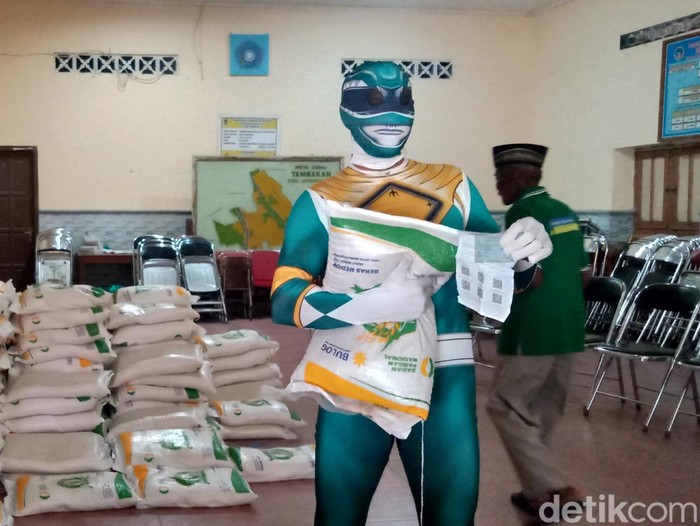 Sarijo, warga Desa Tambakan, Kecamatan Jogonalan, Kabupaten Klaten, mengambil beras bantuan 10 kg dengan kostum superhero ala Power Rangers, Selasa (20/2/2024).