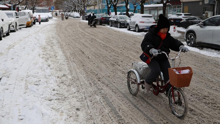 Berjibaku Bersihkan Salju Tebal di Jalanan Beijing A woman walks on a snow-covered path following snowfall in Beijing, China February 21, 2024. REUTERS/Florence Lo