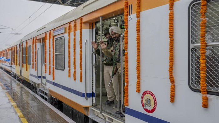 Security men react to camera as they stand inside the first electric train in the Kashmir valley on the outskirts of Srinagar, Indian controlled Kashmir, Tuesday, Feb. 20, 2024. Prime Minister Narendra Modi on Tuesday virtually flagged off the train service between Sangaldan station and Baramulla station during a public rally in Jammu. (AP Photo/Dar Yasin)