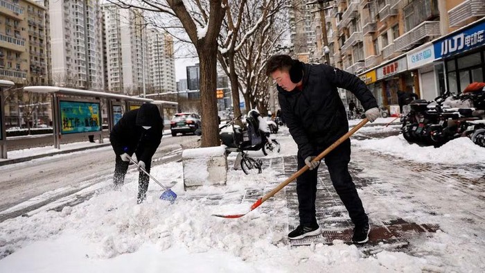 Workers clear snow off a pedestrian road following snowfall in Beijing, China February, 21, 2024. REUTERS/Tingshu Wang Purchase Licensing Rights