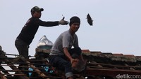 Warga turunkan genteng di atas kios bengkel karena banyak genteng yang pecah tersapu angin dan tertimpa batang pohon. (Foto: Wisma Putra/detikJabar)