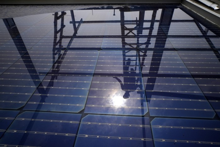 A worker of Solar Square is reflected in a panel filled with rain as he erects the pillars for placing solar panels on the rooftop of a residence in Gurugram on the outskirts of New Delhi, India, Tuesday, Feb. 20, 2024. India is renewing its push to add rooftop solar to meet the needs of a fast-growing nation thats hungry for energy. (AP Photo/Manish Swarup)
