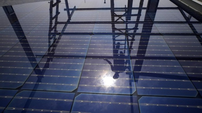 A worker of Solar Square is reflected in a panel filled with rain as he erects the pillars for placing solar panels on the rooftop of a residence in Gurugram on the outskirts of New Delhi, India, Tuesday, Feb. 20, 2024. India is renewing its push to add rooftop solar to meet the needs of a fast-growing nation thats hungry for energy. (AP Photo/Manish Swarup)
