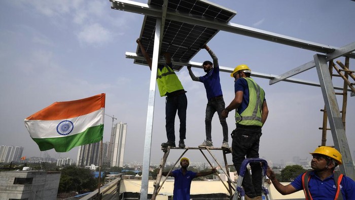 A worker of Solar Square is reflected in a panel filled with rain as he erects the pillars for placing solar panels on the rooftop of a residence in Gurugram on the outskirts of New Delhi, India, Tuesday, Feb. 20, 2024. India is renewing its push to add rooftop solar to meet the needs of a fast-growing nation that's hungry for energy. (AP Photo/Manish Swarup)