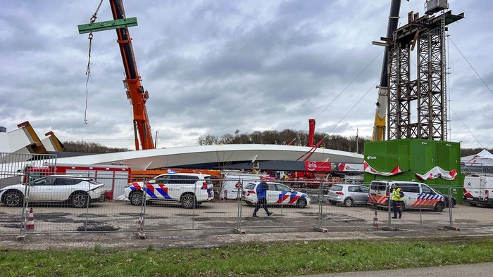 Emergency workers and police stand at the site where two people died and two more were injured in Lochem, easter Netherlands, Wednesday, Feb. 21, 2024, when part of a new bridge being built over a canal collapsed, emergency services said. The accident happened in Lochem, 130 kilometers (80 miles) east of Amsterdam, as workers lifted a large metal arch into place as part of the bridge construction. (AP Photo/Rens Hulman)