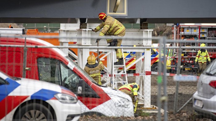 Emergency workers and police stand at the site where two people died and two more were injured in Lochem, easter Netherlands, Wednesday, Feb. 21, 2024, when part of a new bridge being built over a canal collapsed, emergency services said. The accident happened in Lochem, 130 kilometers (80 miles) east of Amsterdam, as workers lifted a large metal arch into place as part of the bridge construction. (AP Photo/Rens Hulman)