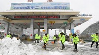 Para pekerja membersihkan salju dari stasiun tol setelah hujan salju di daerah Baokang, Xiangyang, provinsi Hubei. cnsphoto via REUTERS