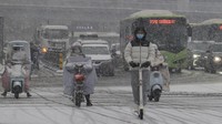 Pengendara melintasi jalan saat hujan salju di Xian di provinsi Shaanxi, China barat laut. Chinatopix via AP