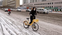 Seorang wanita mendorong sepeda di jalan setelah hujan salju di Beijing. REUTERS/Tingshu Wang