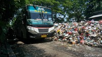 Tumpukan sampah tersebut memakan separuh jalan. Bus yang melintas harus memperlambat laju.