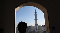 Seorang anak melihat sebuah masjid yang tinggal menaranya setelah hancur dibom Israel.  