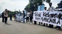 Mereka juga membawa atribut aksi seperti poster dan spanduk. 