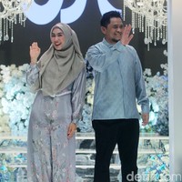 Oki Setiana Dewi bersama suami, Ory Vitrio membawakan koleksi baju Lebaran sarimbit 2024. Oki memakai hijab pashmina syari dipadu dengan dres silk. Sedangkan Ori tampil dengan baju koko bahan silk dan celana hita Foto: Mohammad Abduh/detikcom.