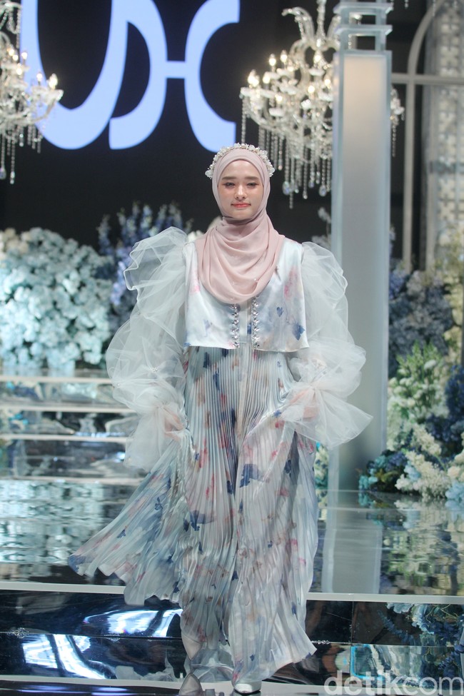 Inara Rusli memeragakan koleksi baju Lebaran 2024 berupa dress pleats putih kombinasi bunga warna biru dan peach, dipadu dengan hijab pashmina instan warna pastel pink dan headpiece beads. Foto: Mohammad Abduh/detikcom