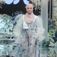 Inara Rusli memeragakan koleksi baju Lebaran 2024 berupa dress pleats putih kombinasi bunga warna biru dan peach, dipadu dengan hijab pashmina instan warna pastel pink dan headpiece beads. Foto: Mohammad Abduh/detikcom
