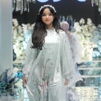 Fujianti Utami Putri memakai dress silk putih dipadu dengan long outer lace, dilengkapi dengan bando dengan detail beads yang membuat semakin feminin. Fuji pun tampil percaya diri dan menebar senyuman saat berlenggok di cat walk. Foto: Mohammad Abduh/detikcom.