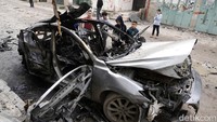 Sejumlah anak bermain di sekitar mobil yang hancur usai diserang drone Israel.