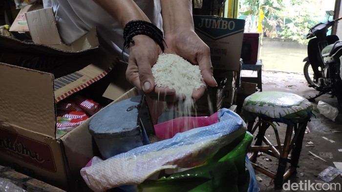 Pedagang menunjukkan beras di Pasar Sekanak Palembang.