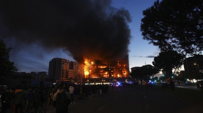 Firefighters work as a housing block burns in Valencia, Spain, Thursday, Feb. 22, 2024. A fire has engulfed two residential buildings in the eastern Spanish city of Valencia, injuring at least 13 people. Flames can be seen bursting out from windows and balconies of the 14-story residential building where it is reported to have started. Emergency service reports say at least 13 people were injured. Firefighters have rushed to the area located on an avenue in the city center. Some people were trapped on balconies. (AP Photo/Alberto Saiz)