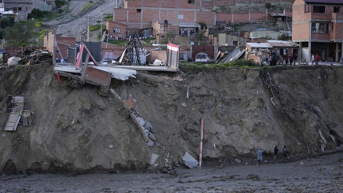 Puluhan Rumah di Bantaran Sungai Bolivia Runtuh Tergerus Longsor Municipal workers use heavy equipment to remove sludge from a riverbed, where a mudslide due to persistent rains damaged several homes on the banks of the Irpavi 2 river, in La Paz, Bolivia, Thursday, Feb. 22, 2024. (AP Photo/Juan Karita)