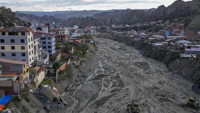 Municipal workers use heavy equipment to remove sludge from a riverbed, where a mudslide due to persistent rains damaged several homes on the banks of the Irpavi 2 river, in La Paz, Bolivia, Thursday, Feb. 22, 2024. (AP Photo/Juan Karita)