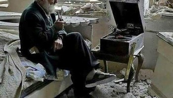 Seorang pria mendengarkan fonograf di kamar tidurnya hancur di Allepo Suriah pada tahun 2017. Jepretan ini adalah karya fotografer Joseph Eid. Foto: Boredpanda