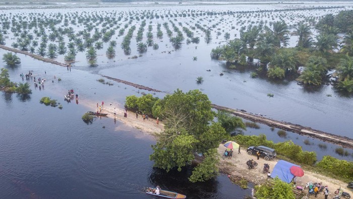 Warga berdiri di jalan yang terendam banjir di Gunung Mas, Tanjung Jabung Barat, Jambi, Jumat (23/2/2024). Banjir yang terjadi sejak beberapa hari terakhir dan merendam jalan serta areal perkebunan setempat itu oleh sebagian warga dimanfaatkan sebagai tempat bermain dan berwisata. ANTARA FOTO/Wahdi Septiawan/aww.
