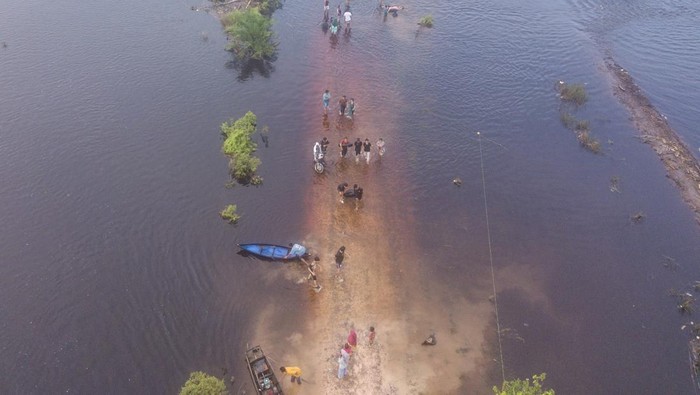 Warga berdiri di jalan yang terendam banjir di Gunung Mas, Tanjung Jabung Barat, Jambi, Jumat (23/2/2024). Banjir yang terjadi sejak beberapa hari terakhir dan merendam jalan serta areal perkebunan setempat itu oleh sebagian warga dimanfaatkan sebagai tempat bermain dan berwisata. ANTARA FOTO/Wahdi Septiawan/aww.