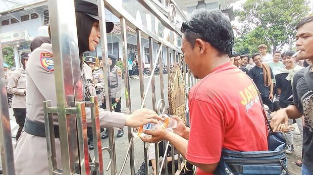 Momen Polwan bagikan minuman kepada para pendemo penundaan Pilkades di Banjarnegara.