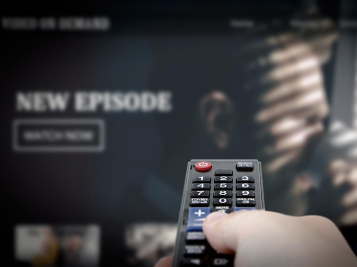 Ilustrasi Nonton Film VOD service on television. Man watching TV, streaming service, video on demand, remote control in hand.