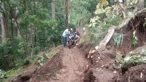 Empat warga menggotong sepeda motor melewati sekitar 40 meter jalan yang tertimbun material longsor di Desa Gurung, Kecamatan Welak, Manggarai Barat, NTT (Istimewa)