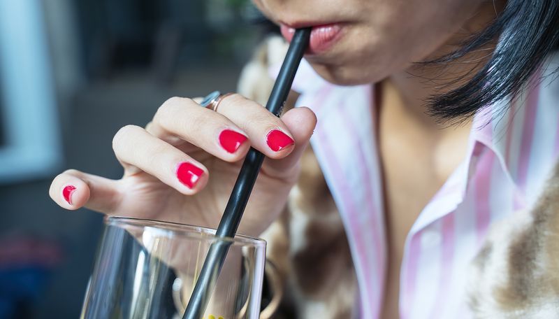 Thirsty woman drinking with straw